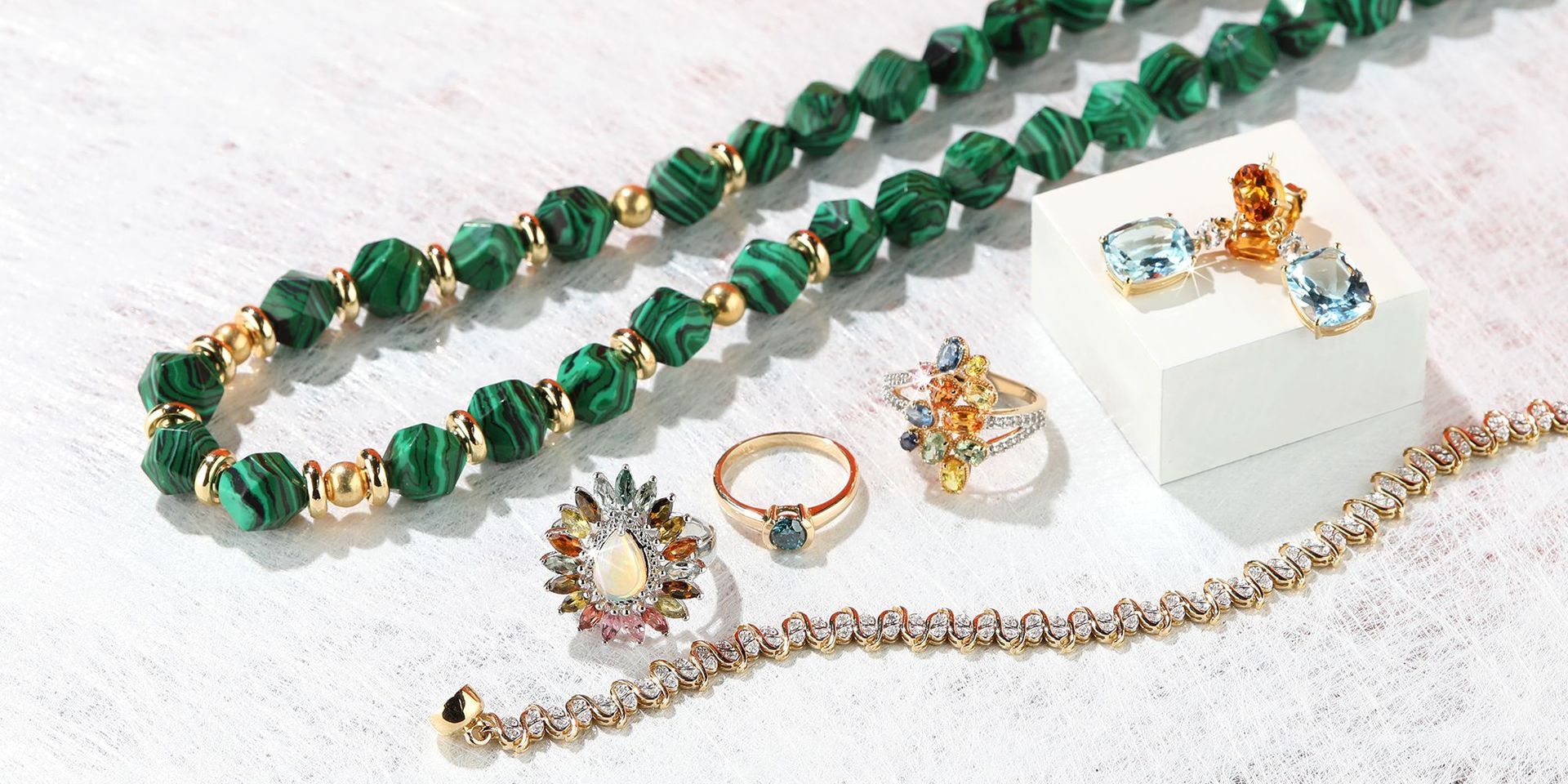 Edelsteinschmuck mit grünen und goldenen Akzenten auf hellem Hintergrund