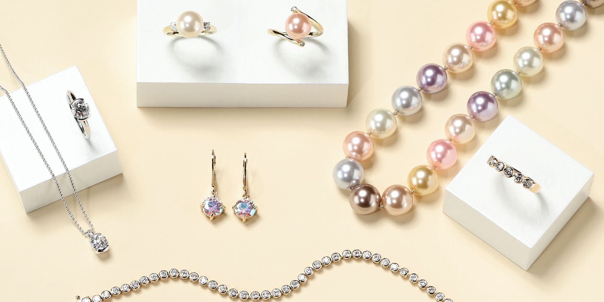 Verschiedene Schmuckstücke, darunter Perlenketten und Ohrringe, auf beigem Hintergrund