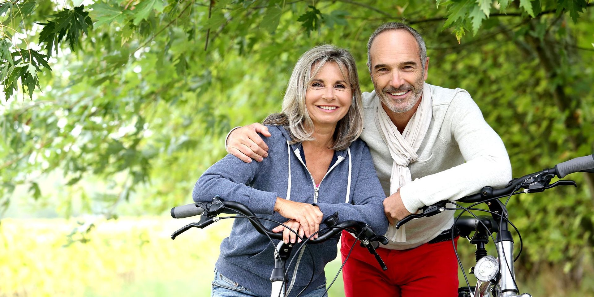 Zwei lächelnde Personen mit Fahrrädern im Grünen, Symbol für Mobilität und Freizeit bei CHANNEL21.