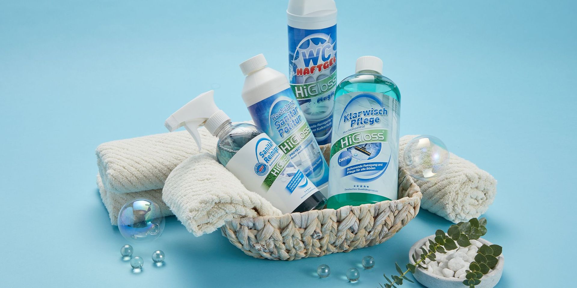 Reinigungsprodukte von HiGloss in einem Korb, präsentiert auf einer blauen Oberfläche.