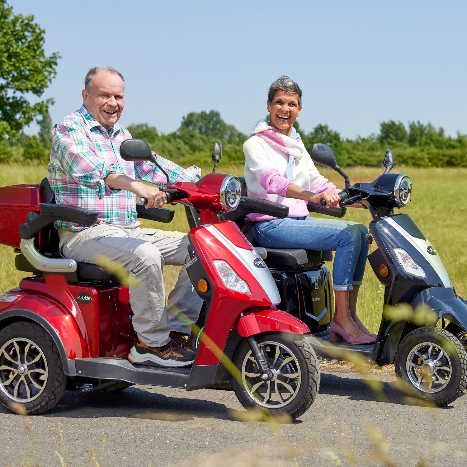 Elektromobile sowie ein Elektrofahrrad stehen auf einem Radweg bei sonnigem Wetter