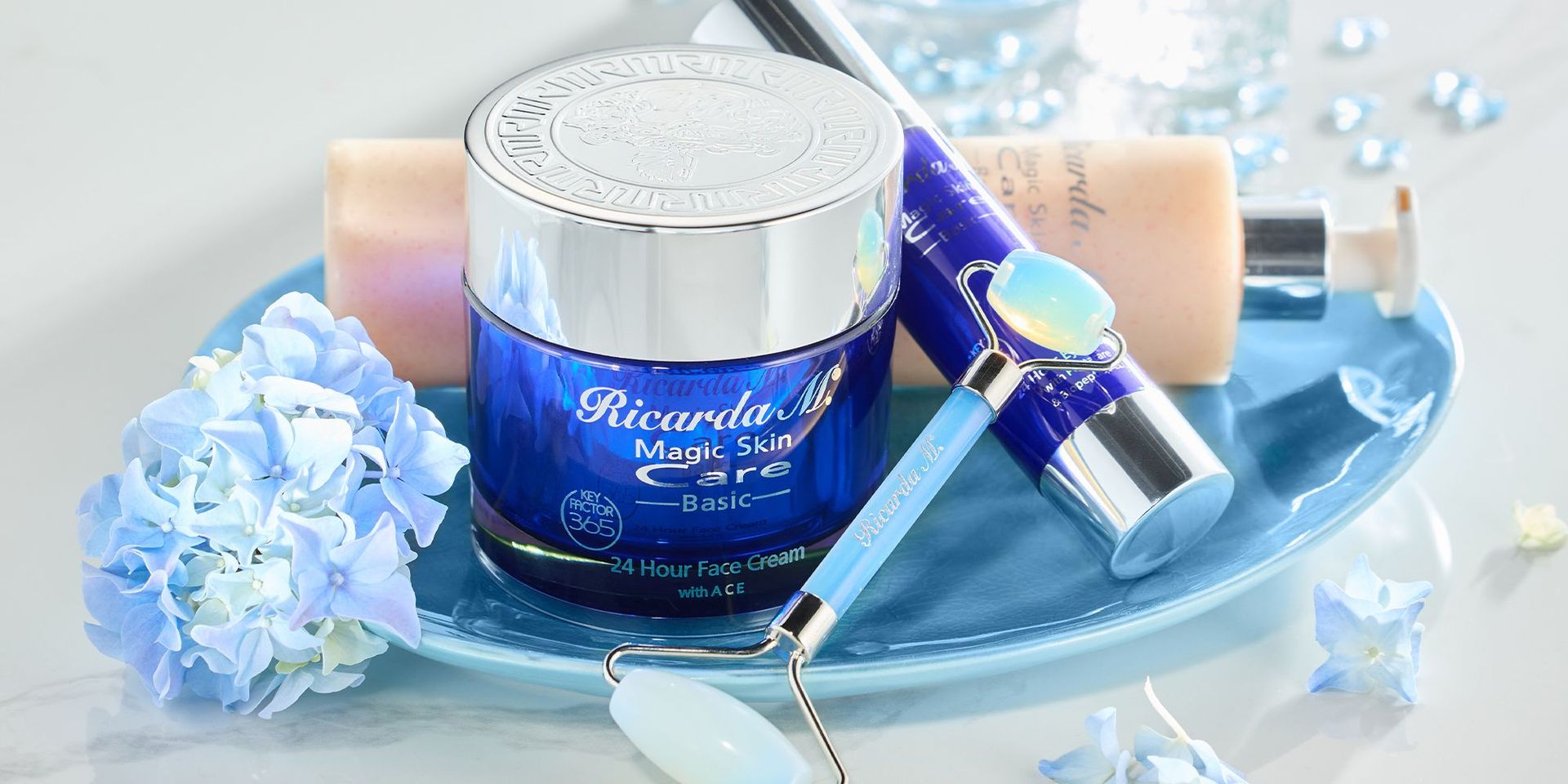Ricarda M. Magic Skin Care Set mit blauen Cremetiegeln und Blumen auf Tablett