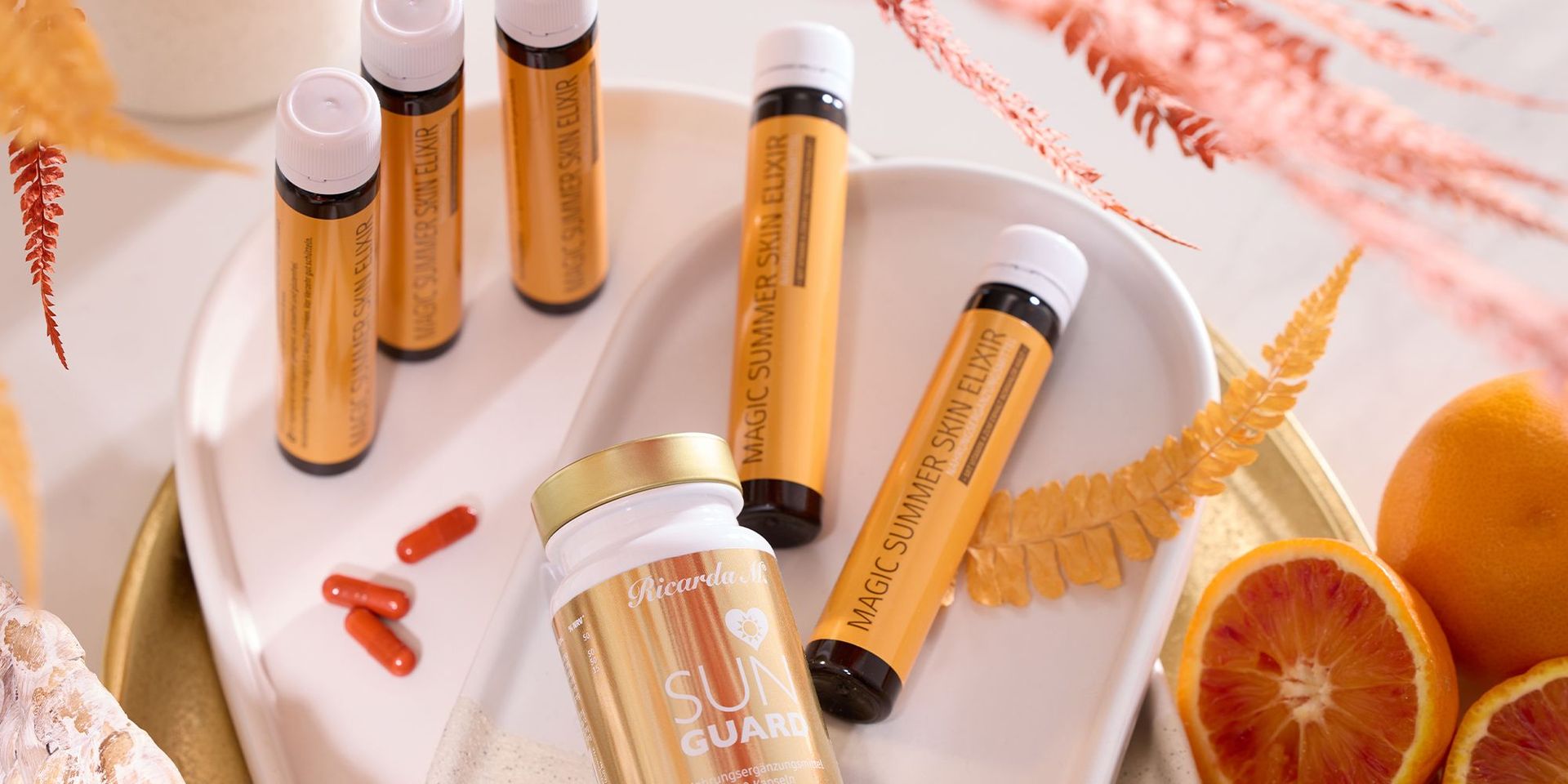 Ricarda M. Sun Guard und Magic Summer Sun Elixier mit Orangen im Hintergrund