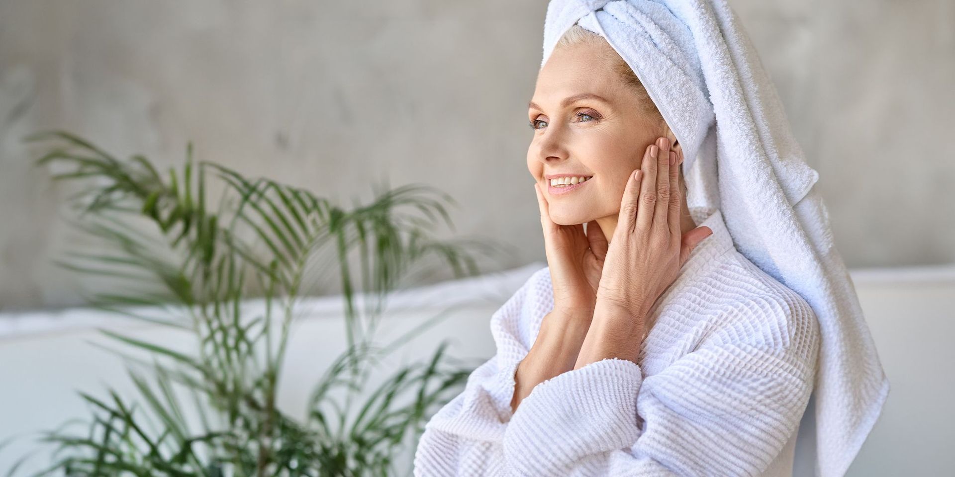 Frau in Bademantel mit einem Haarturban auf dem Kopf vor einer grünen Palme.