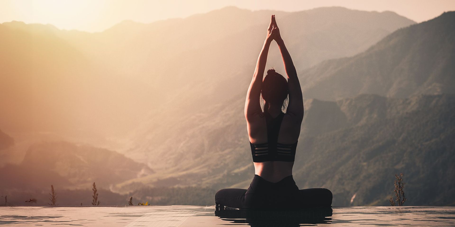 Frau meditiert in den Bergen an einem Pool