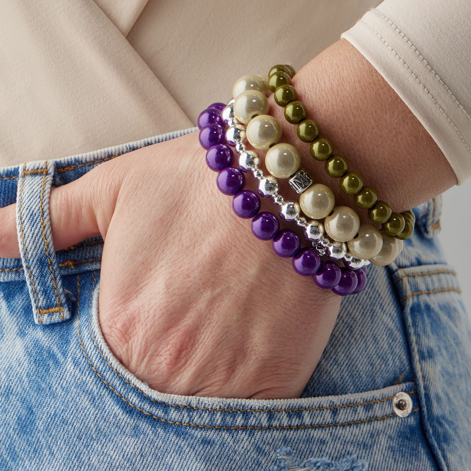 Vier bunte Perlenarmbänder am Arm