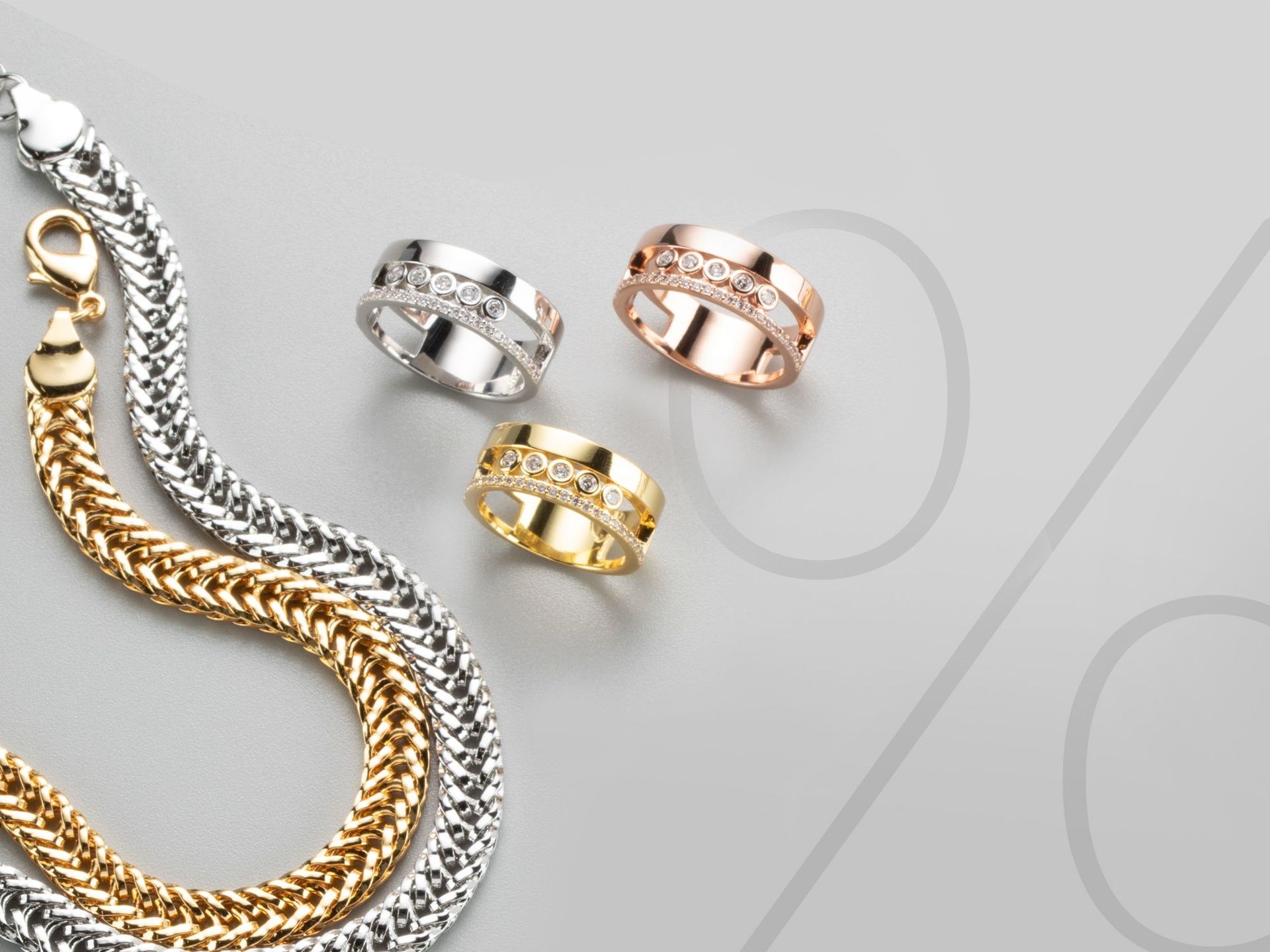 Zwei Halsketten und drei Ringe auf einem grauen Hintergrund