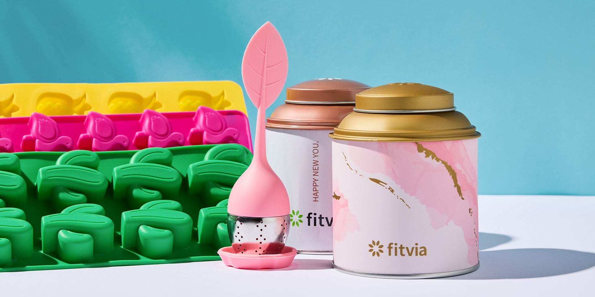 Fitvia Teesieb und Teedosen vor buntem Hintergrund, Fokus auf gesunde Ernährung