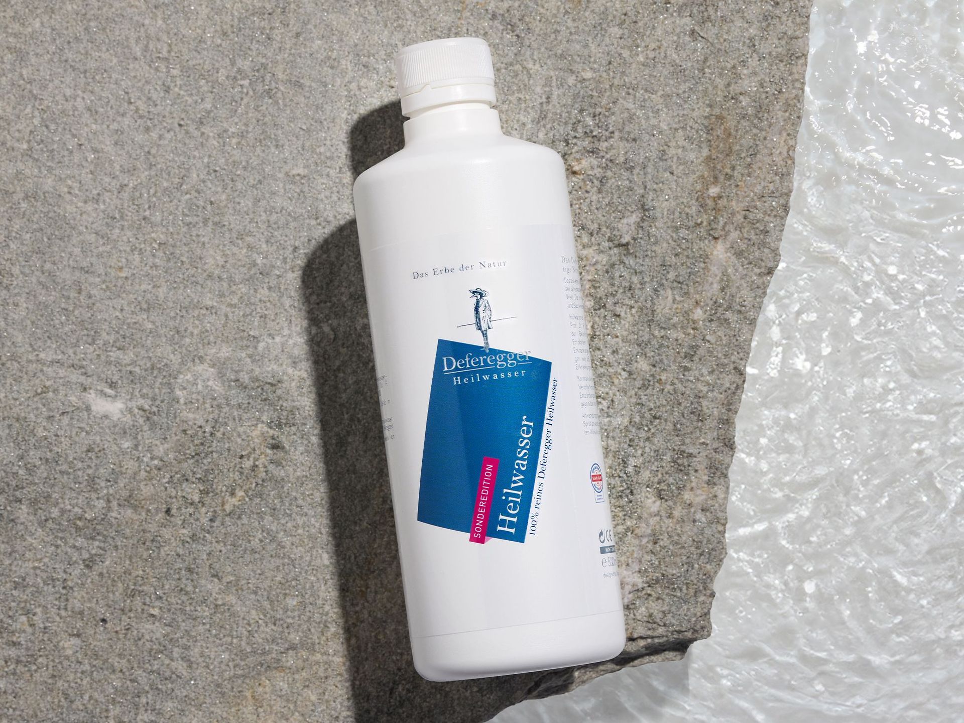 Deferegger Heilwasser pur, 500ml auf einem Stein, der im Wasser liegt