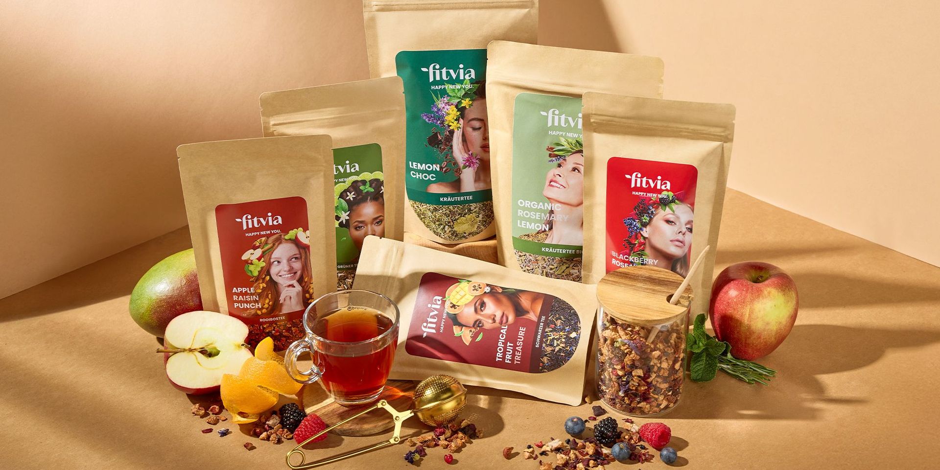 Verschiedene Fitvia-Teeprodukte mit Früchten und Teetasse, Fokus auf gesunde Ernährung.