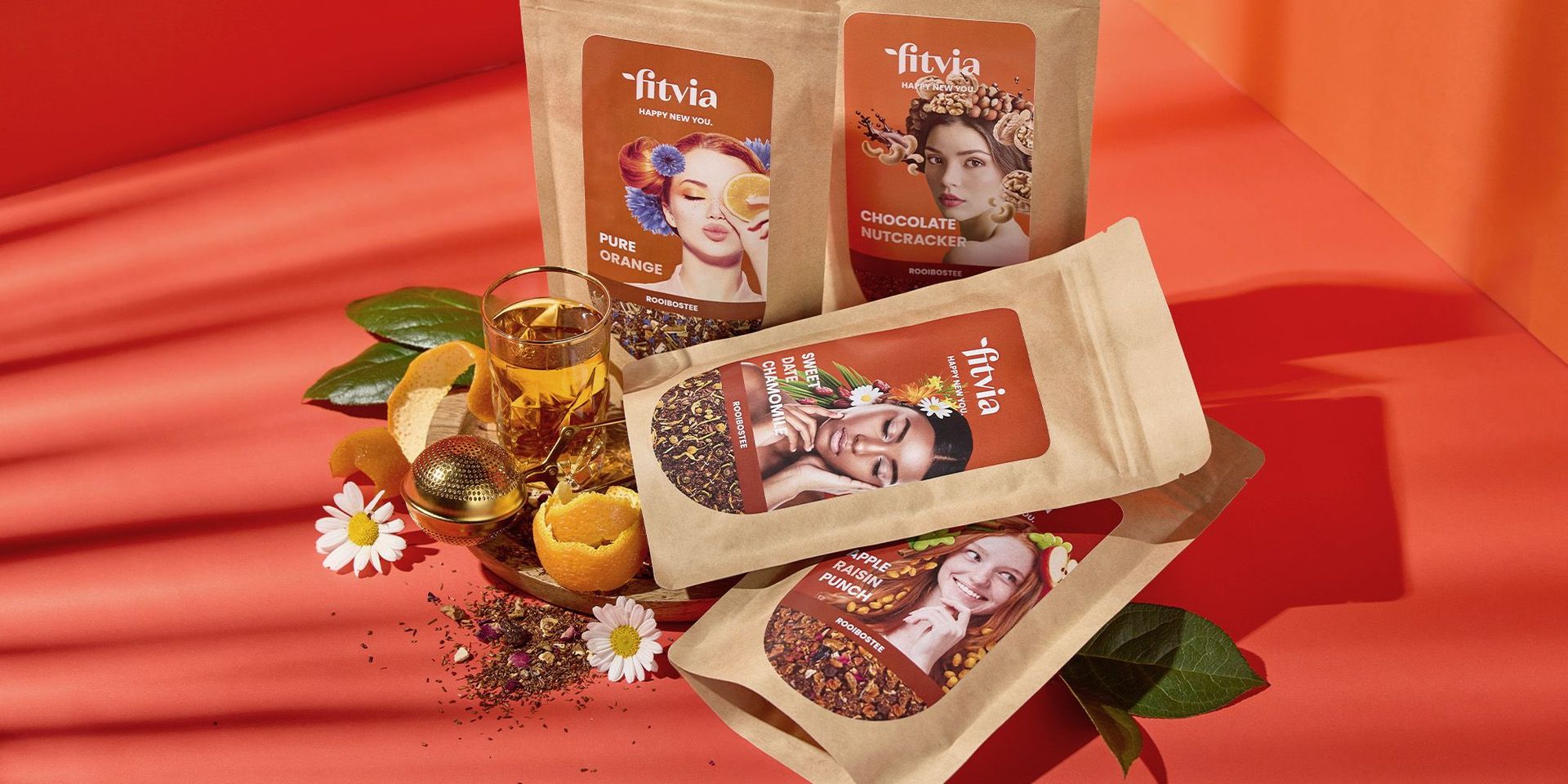 Fitvia Teesorten und Zutaten auf rotem Hintergrund, betont gesunde Ernährung.