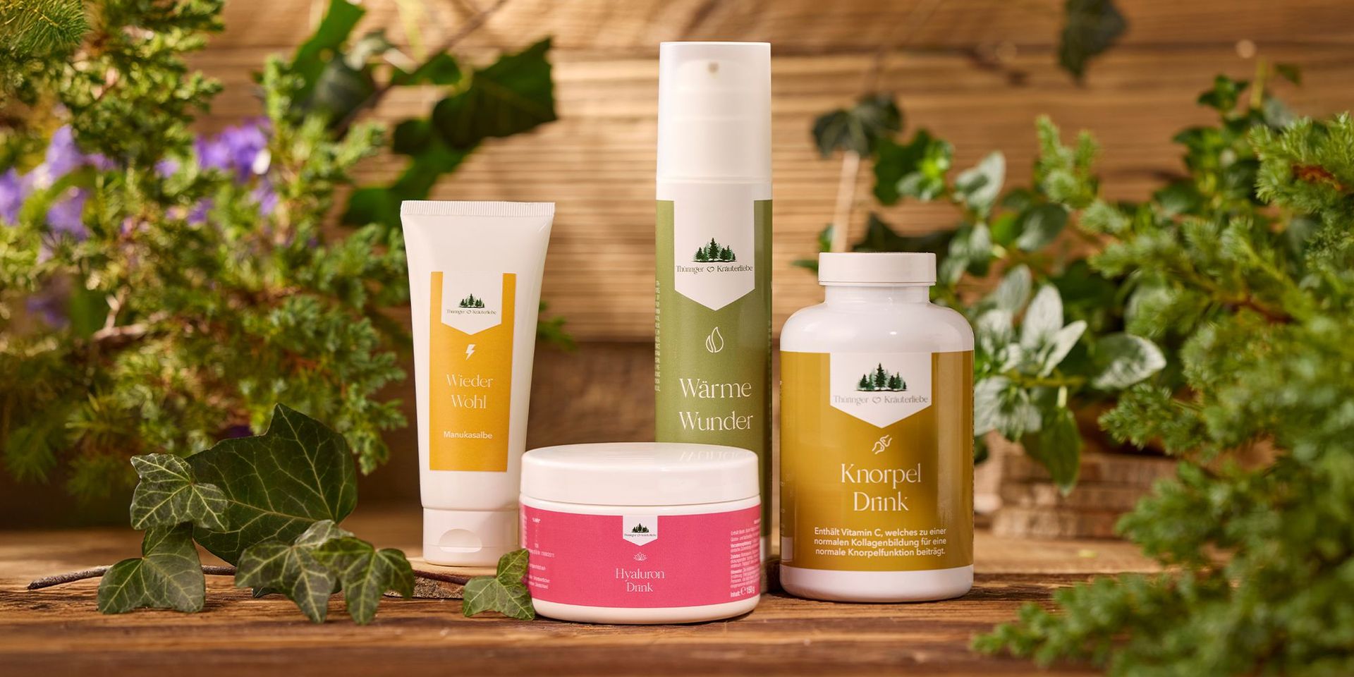 Verschiedene Produkte der Marke Thüringer Kräuterliebe auf einem Holztisch vor einem Holz-Hintergrund