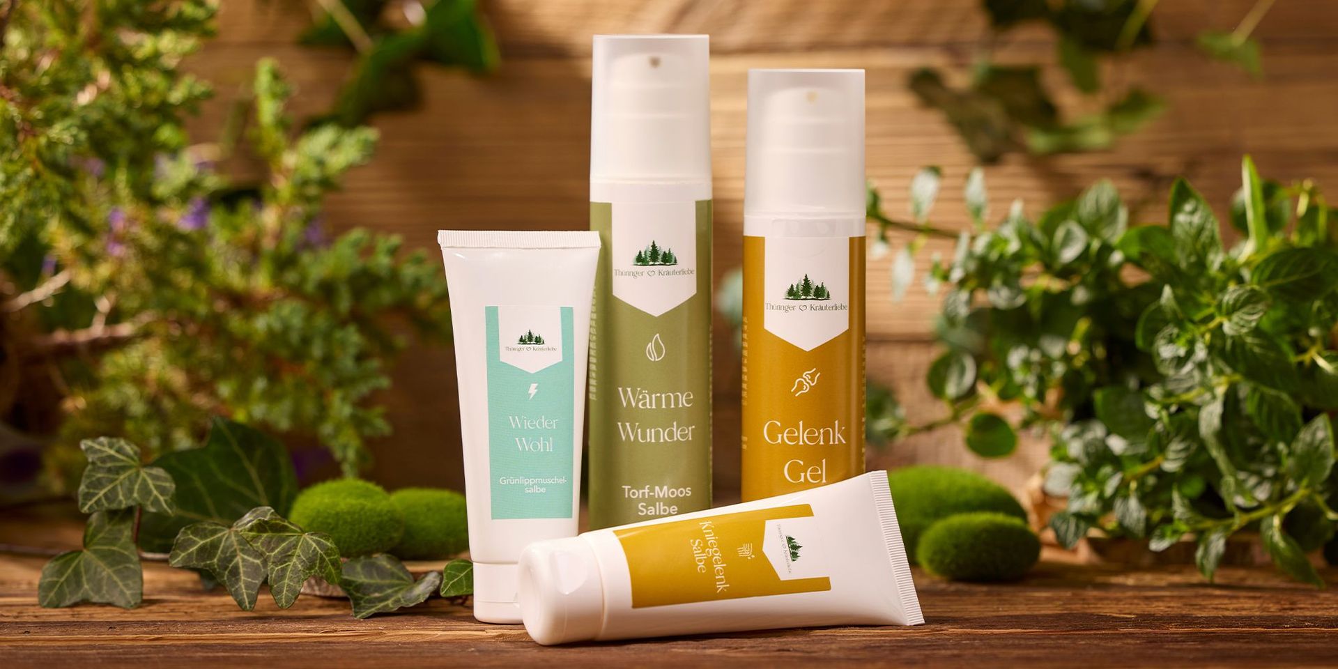 Verschiedene Pflegeprodukte von Thurgauer Kräuterstube auf einem Holztisch, umgeben von grünen Pflanzen.
