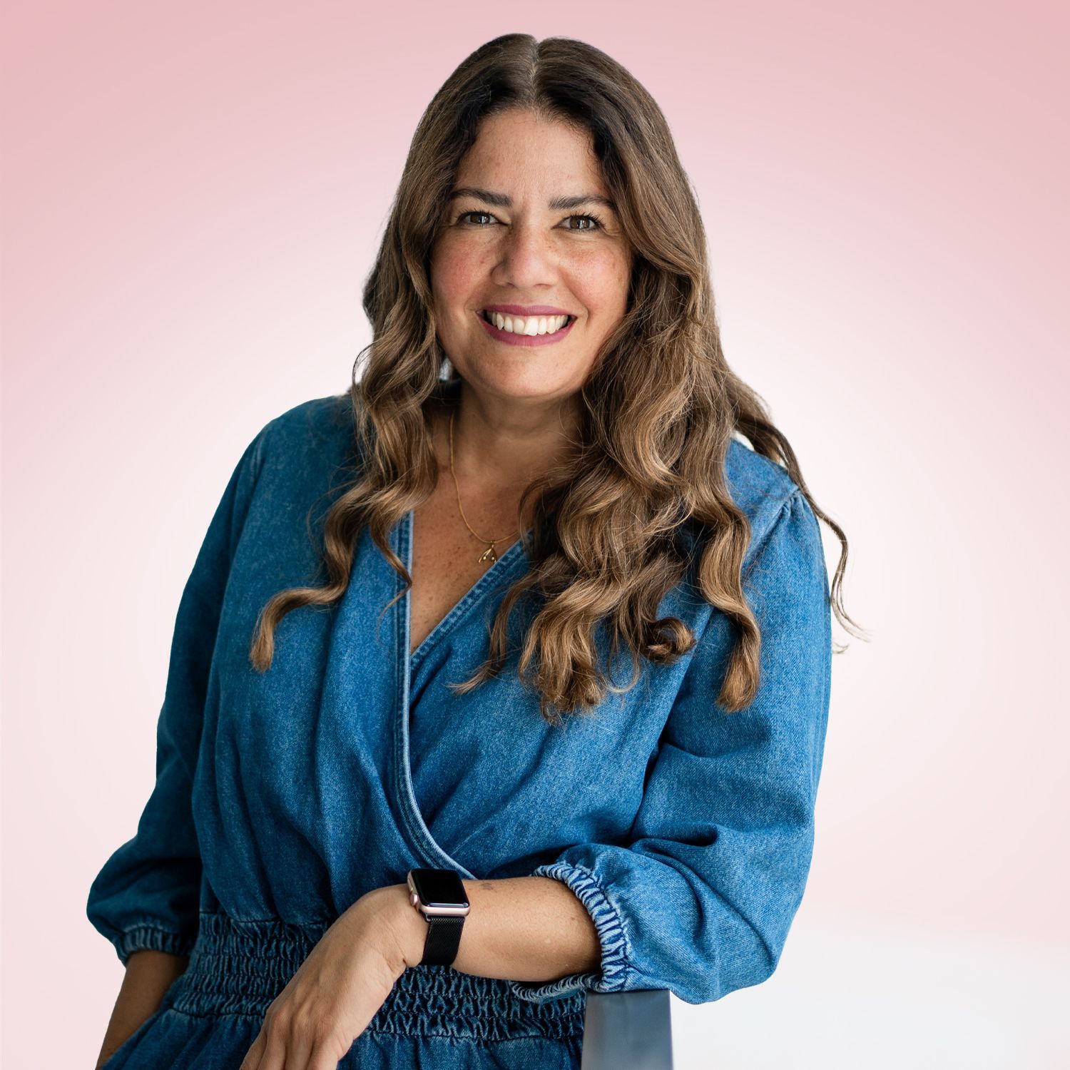 Clarisse Och steht lächelnd vor einem Rosahintergrund