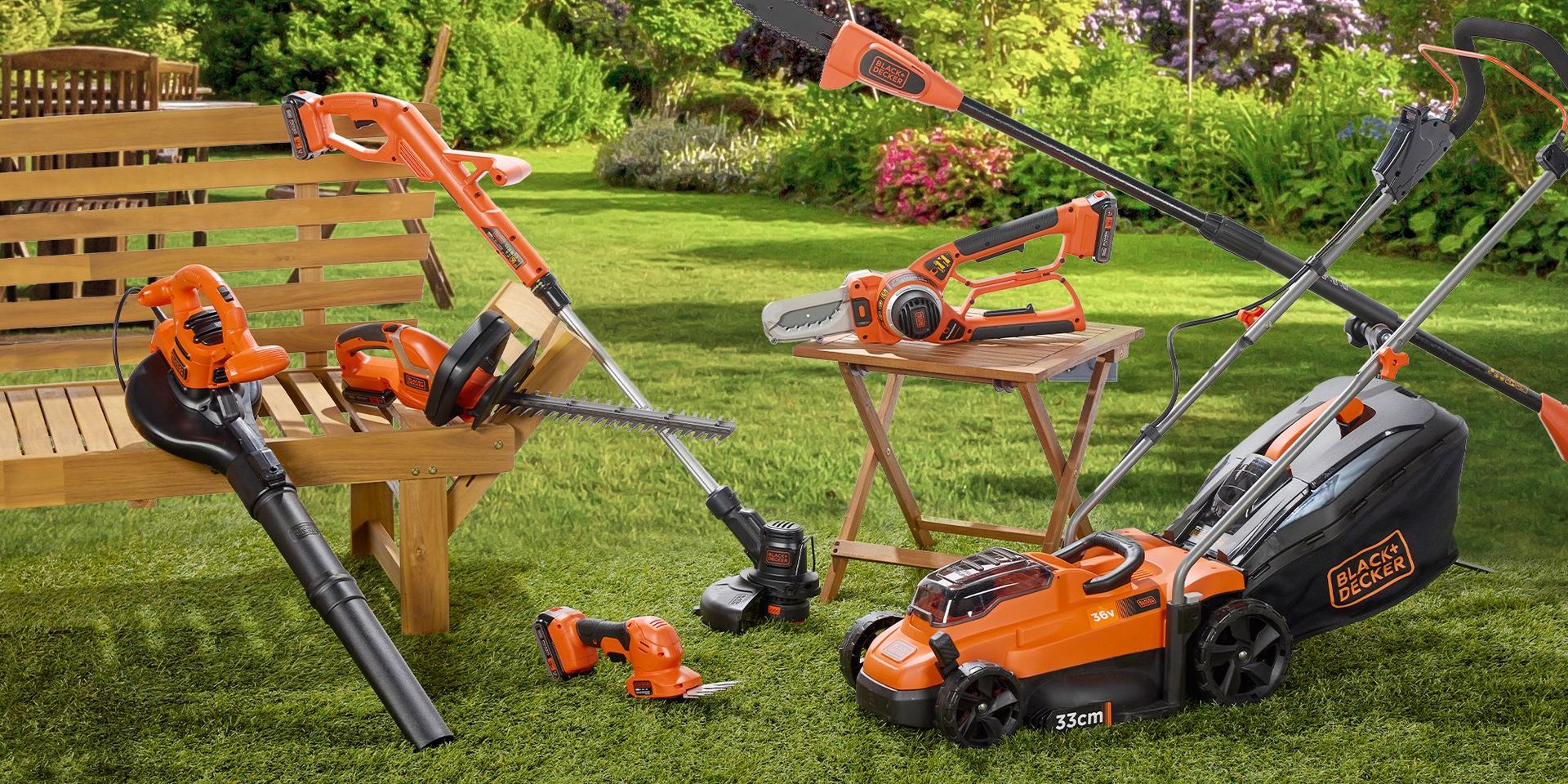 Verschiedene orange-schwarze Black+Decker Gartengeräte auf einer Wiese, darunter Rasenmäher, Heckenschere, Laubbläser und Trimmer