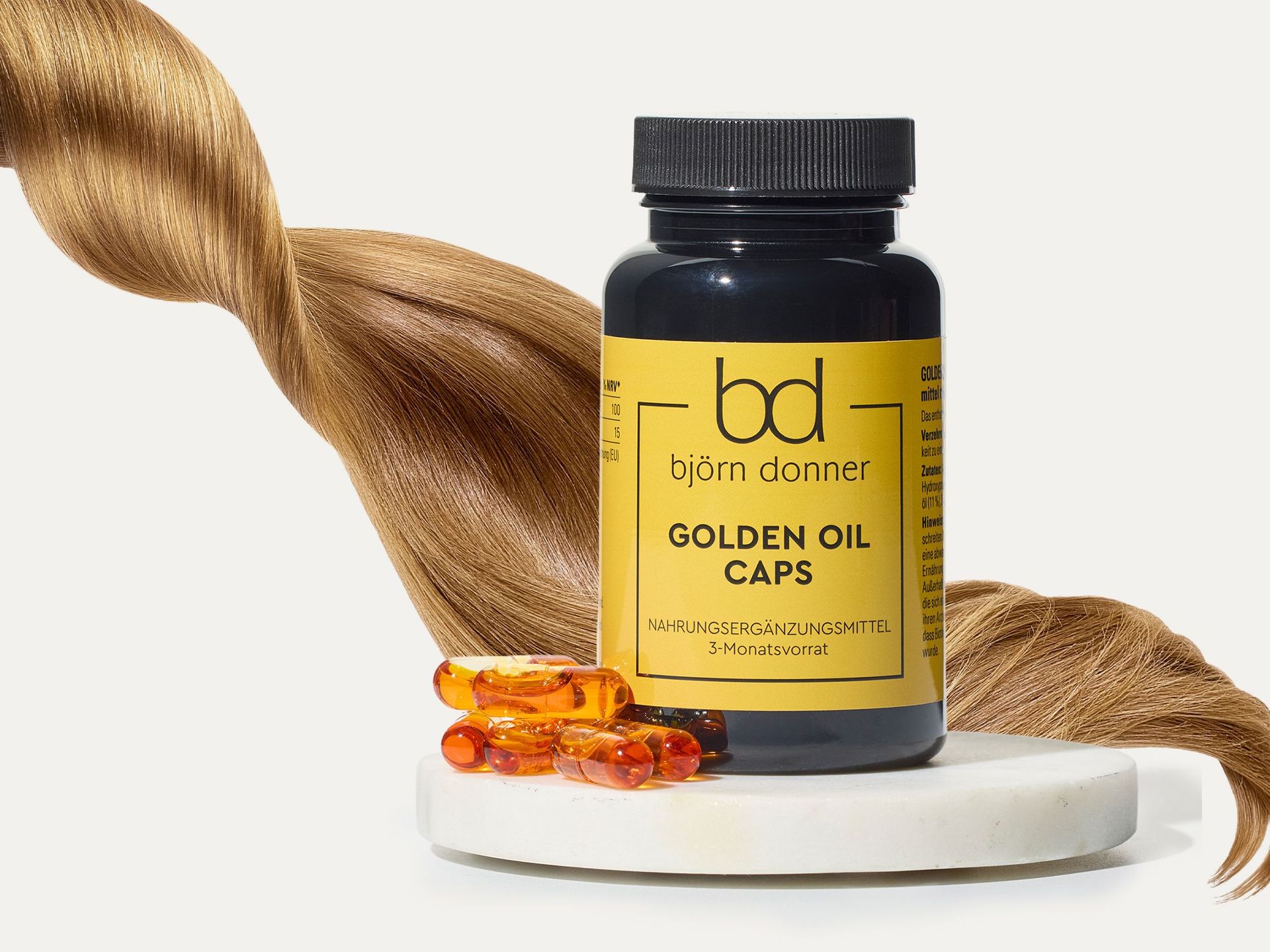 Flasche Björn Donner Golden Oil Caps Nahrungsergänzungsmittel mit goldfarbenen Kapseln und langem blondem Haar im Hintergrund