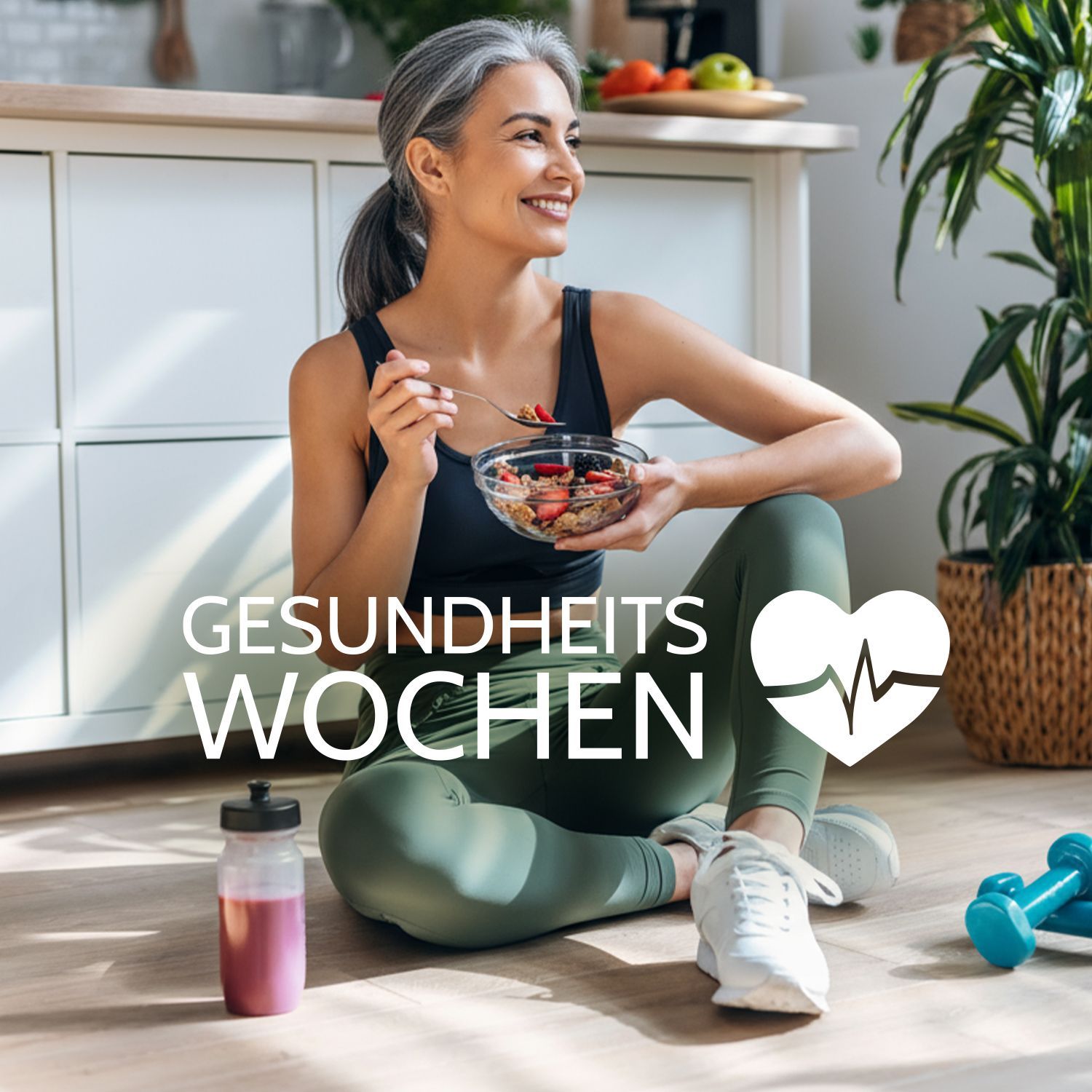 Frau in Sportkleidung sitzt auf dem Boden, hält eine Schüssel mit Obst und isst mit einem Löffel. Daneben liegen Hanteln und eine Trinkflasche.