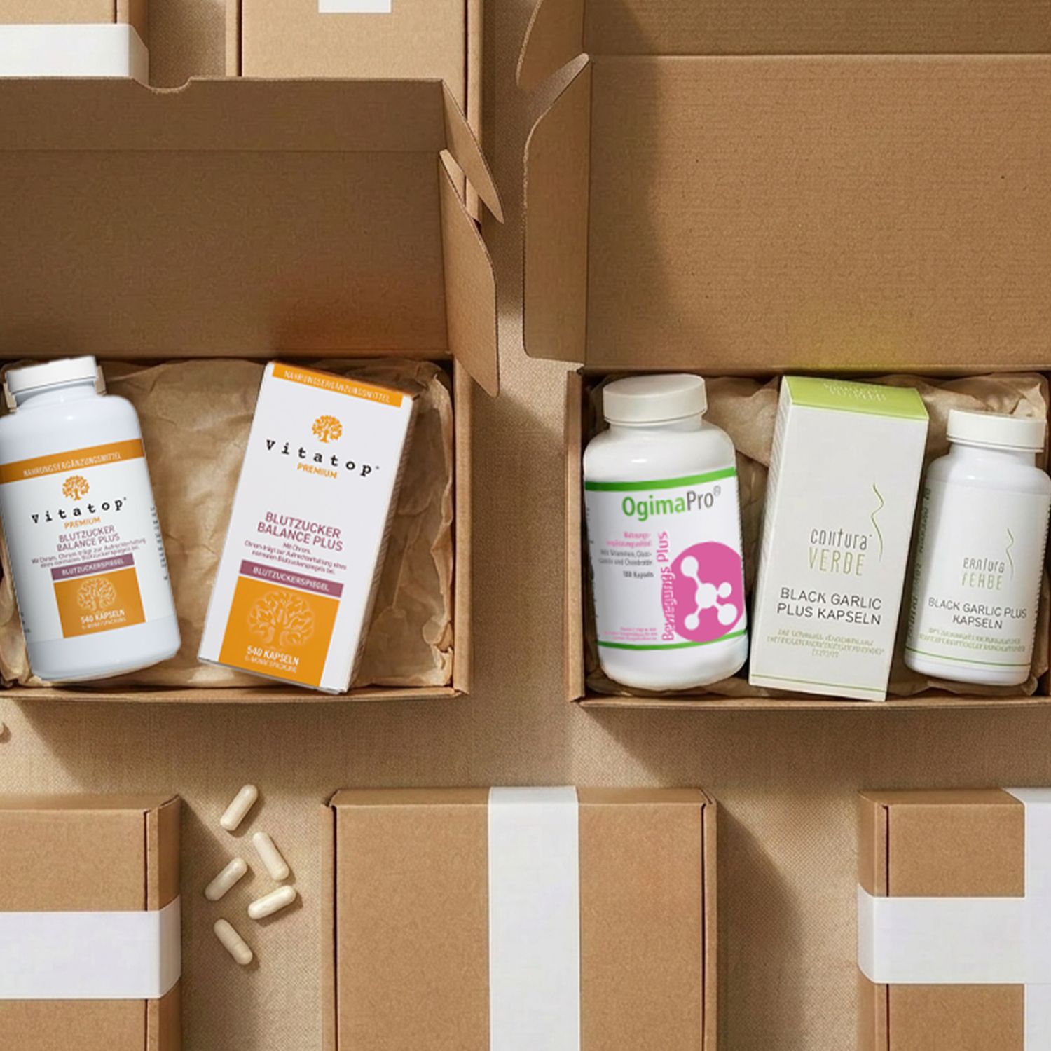 Zwei geöffnete braune Kartons mit Nahrungsergänzungsmitteln in weißen Dosen, links 'Vitatop Blutzucker Balance Plus', rechts 'OgimaPro' und 'contura verde Black Garlic Plus'