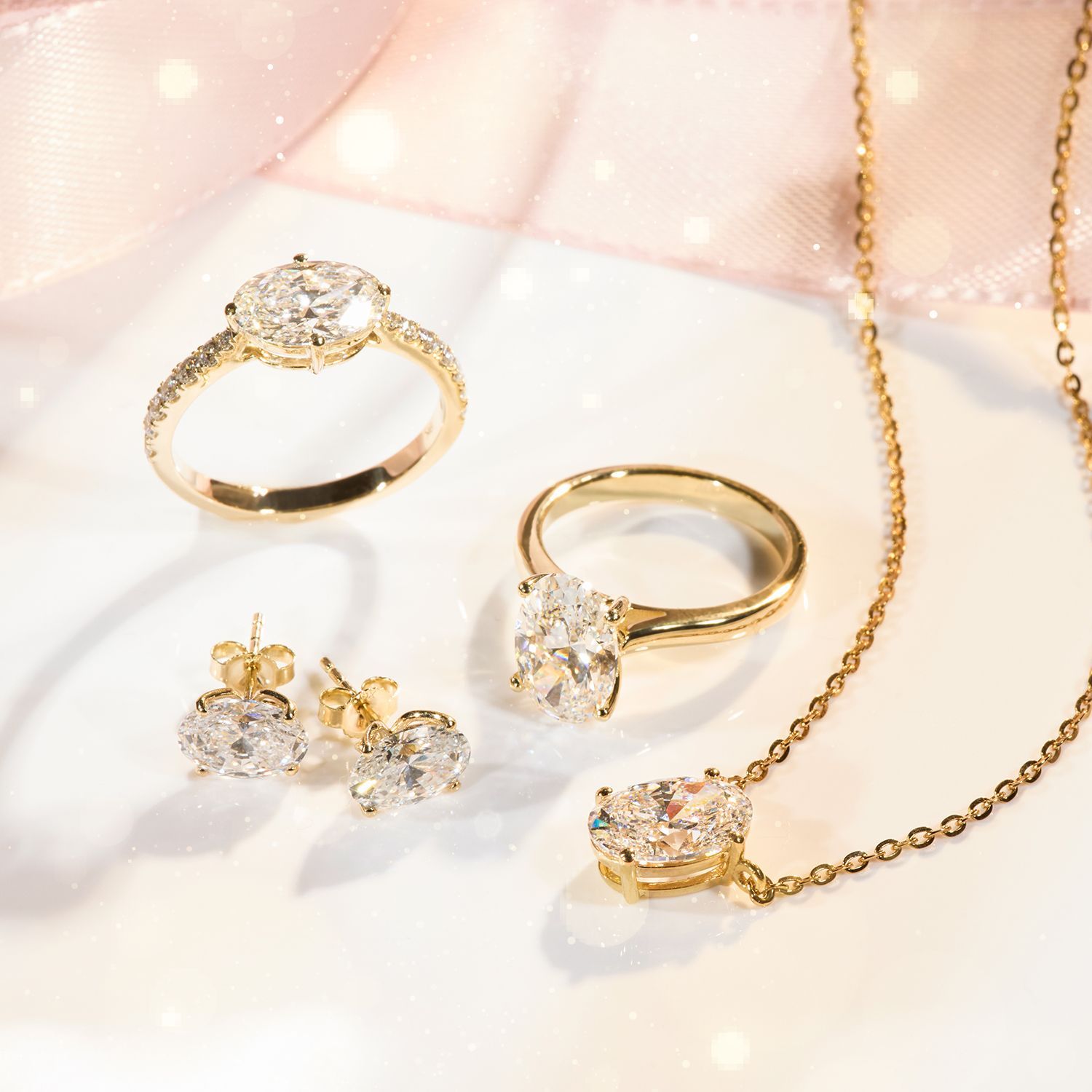 Goldener Schmuck bestehend aus zwei Ringen mit großen ovalen Steinen, einem Paar Ohrsteckern und einer Kette mit Anhänger