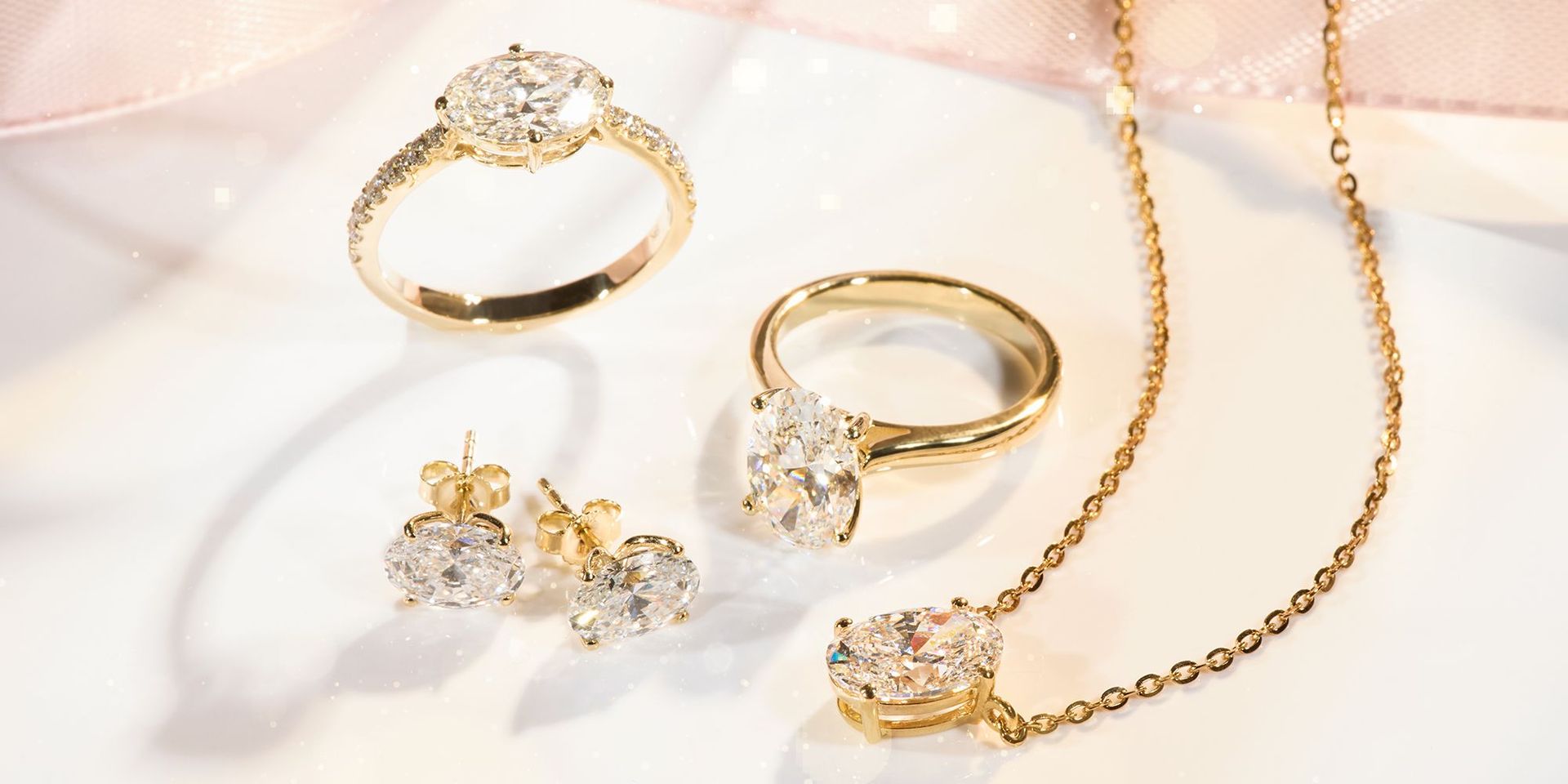 Goldener Schmuck bestehend aus zwei Ringen mit großen ovalen Steinen, einem Paar Ohrsteckern und einer Kette mit Anhänger