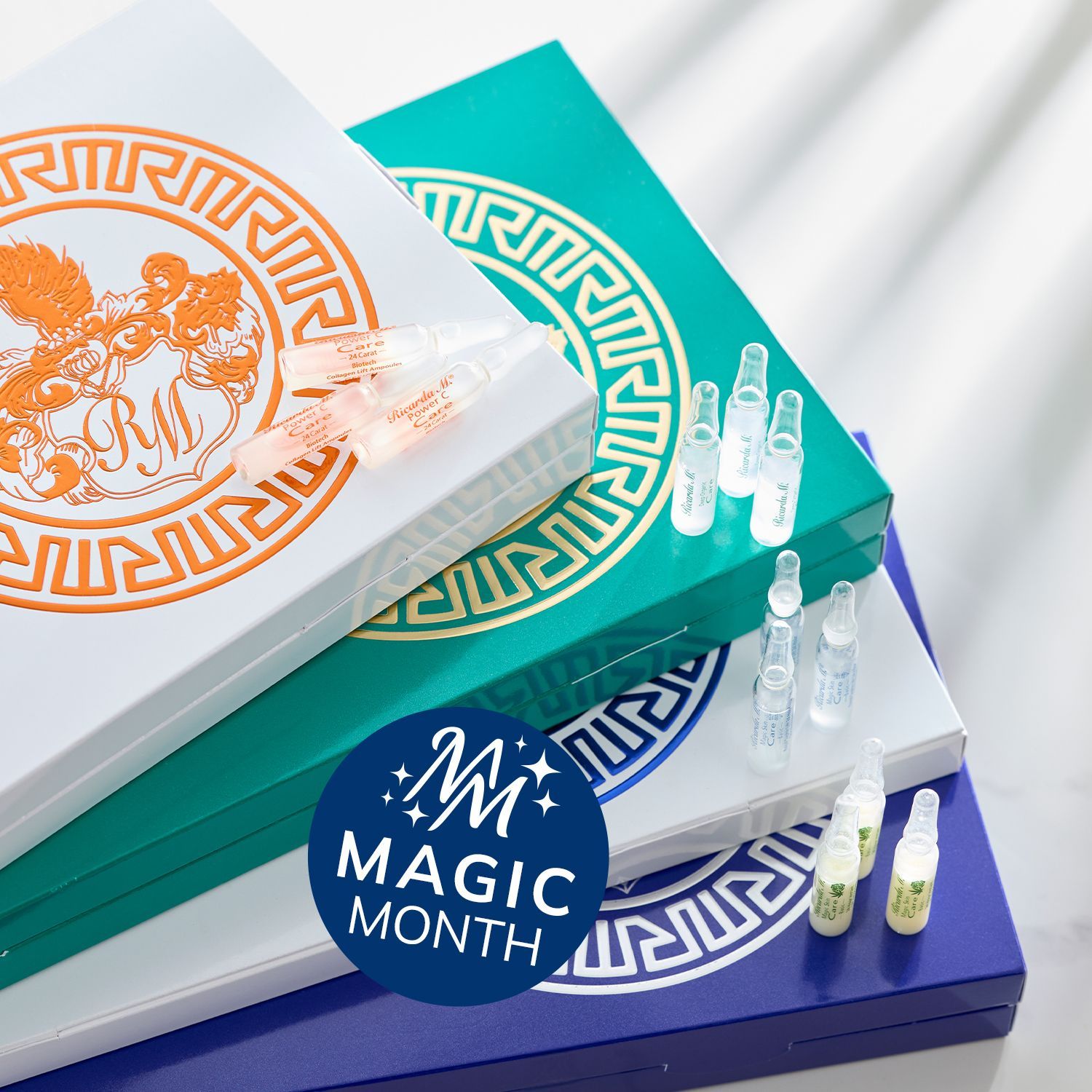 Mehrere gestapelte, rechteckige Verpackungen mit dekorativen Mustern und kleinen durchsichtigen Ampullen darauf