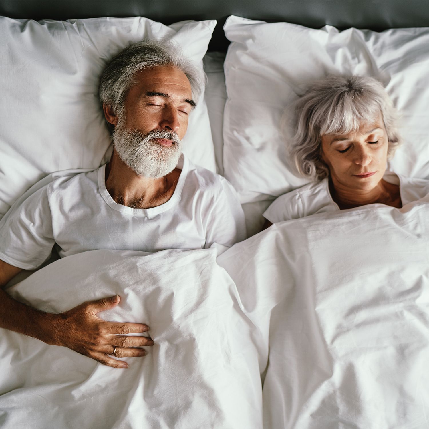 Alles für Ihren Schlaf und Ihre Entspannung Ein älteres Paar schlafend und zugedeckt im Bett.