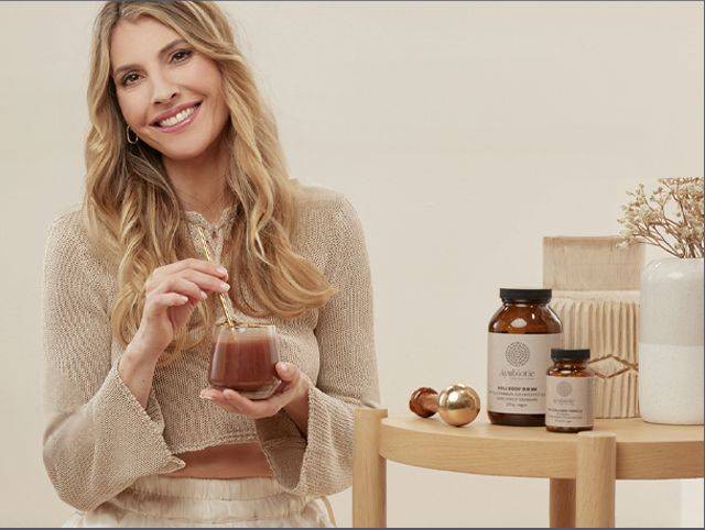Well-Aging mit Ayubiotic® Eine Junge Frau hält ein Glas mit Holi Body Drink