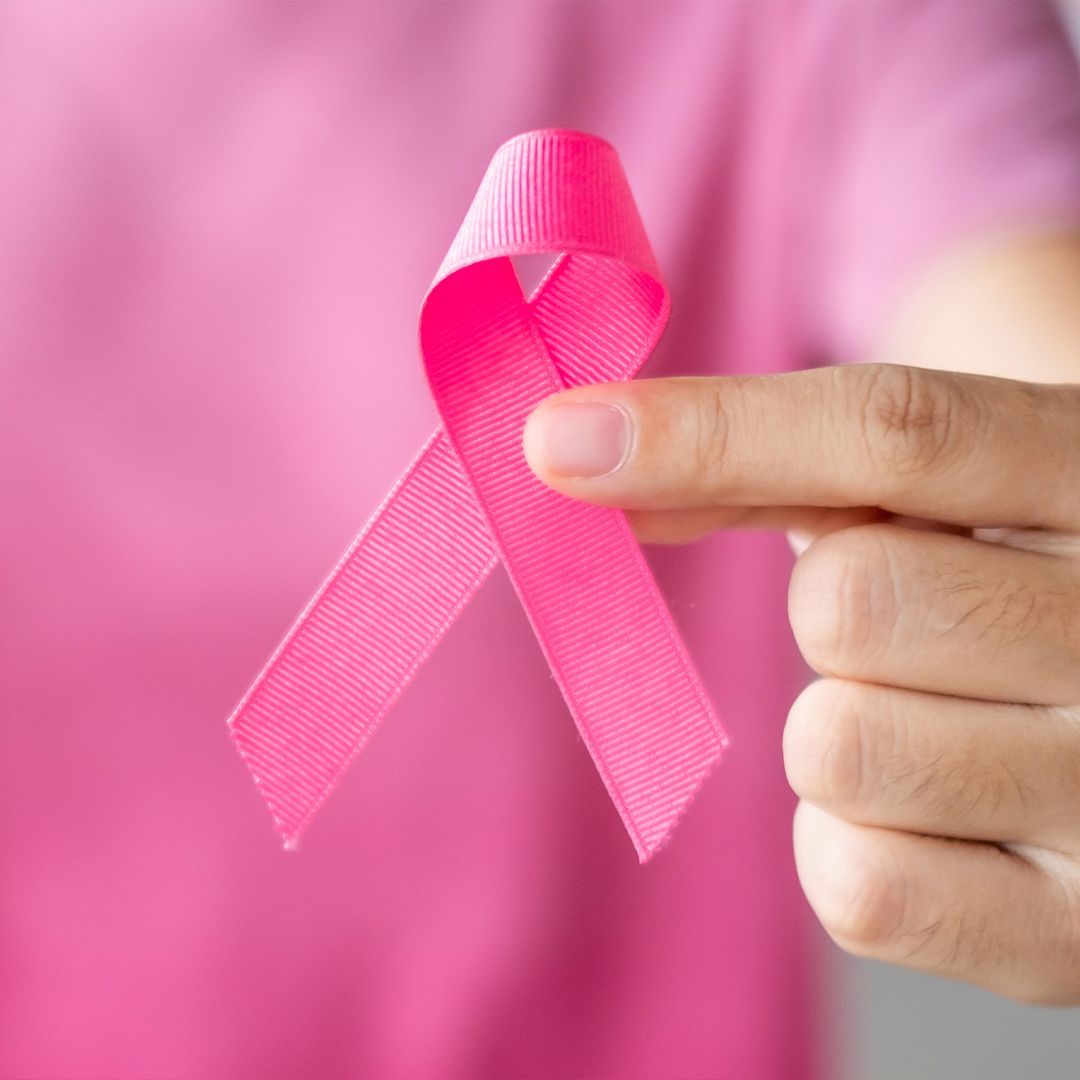 Krebserkrankungen Hand einer Person in rosa Oberteil hält eine pinke Schleife als Symbol für Brustkrebsbewusstsein