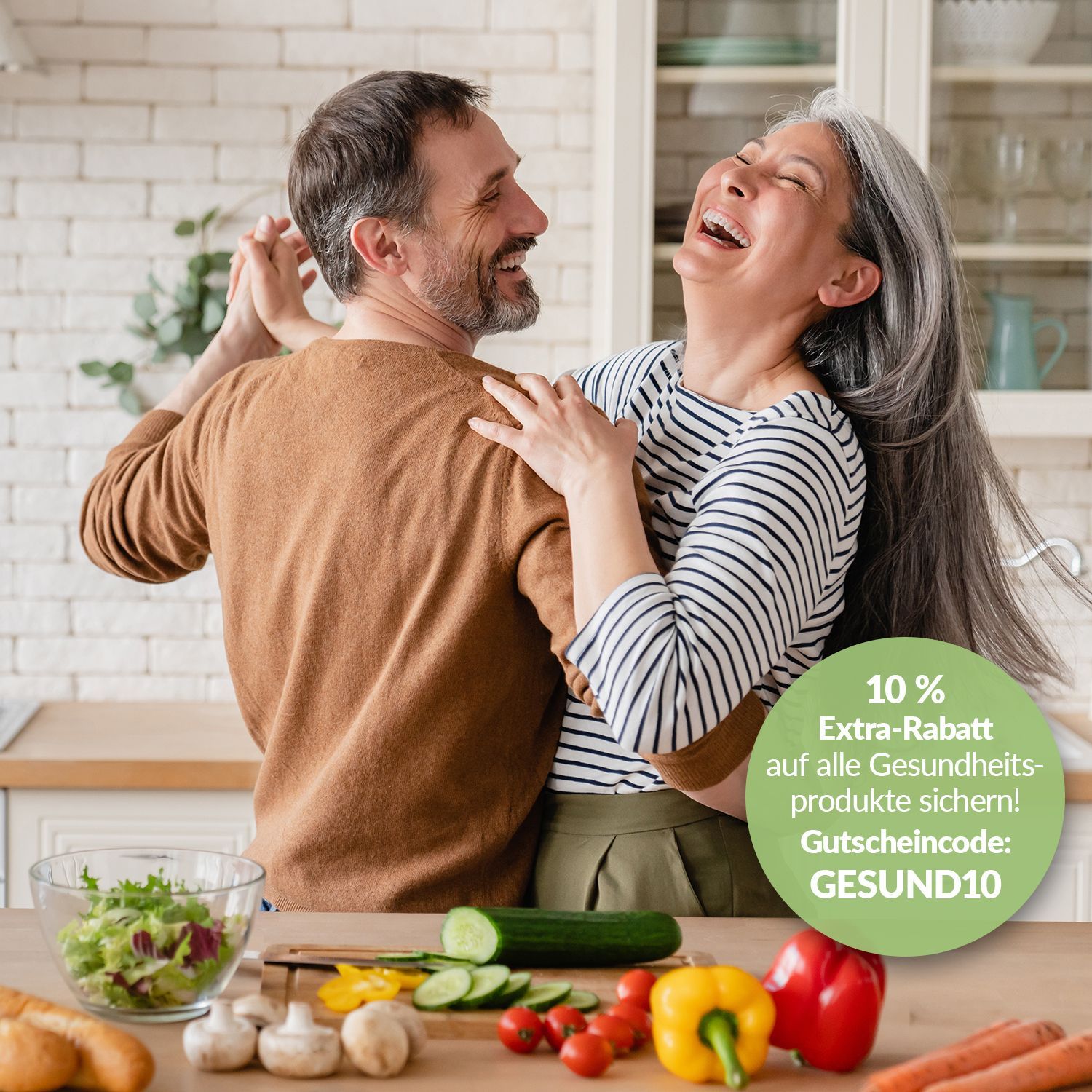 Die CHANNEL21-Gesundheitswochen Zwei Personen umarmen sich in einer hellen Küche, eine hält eine Salatschüssel, auf dem Tisch liegen frisches Gemüse.