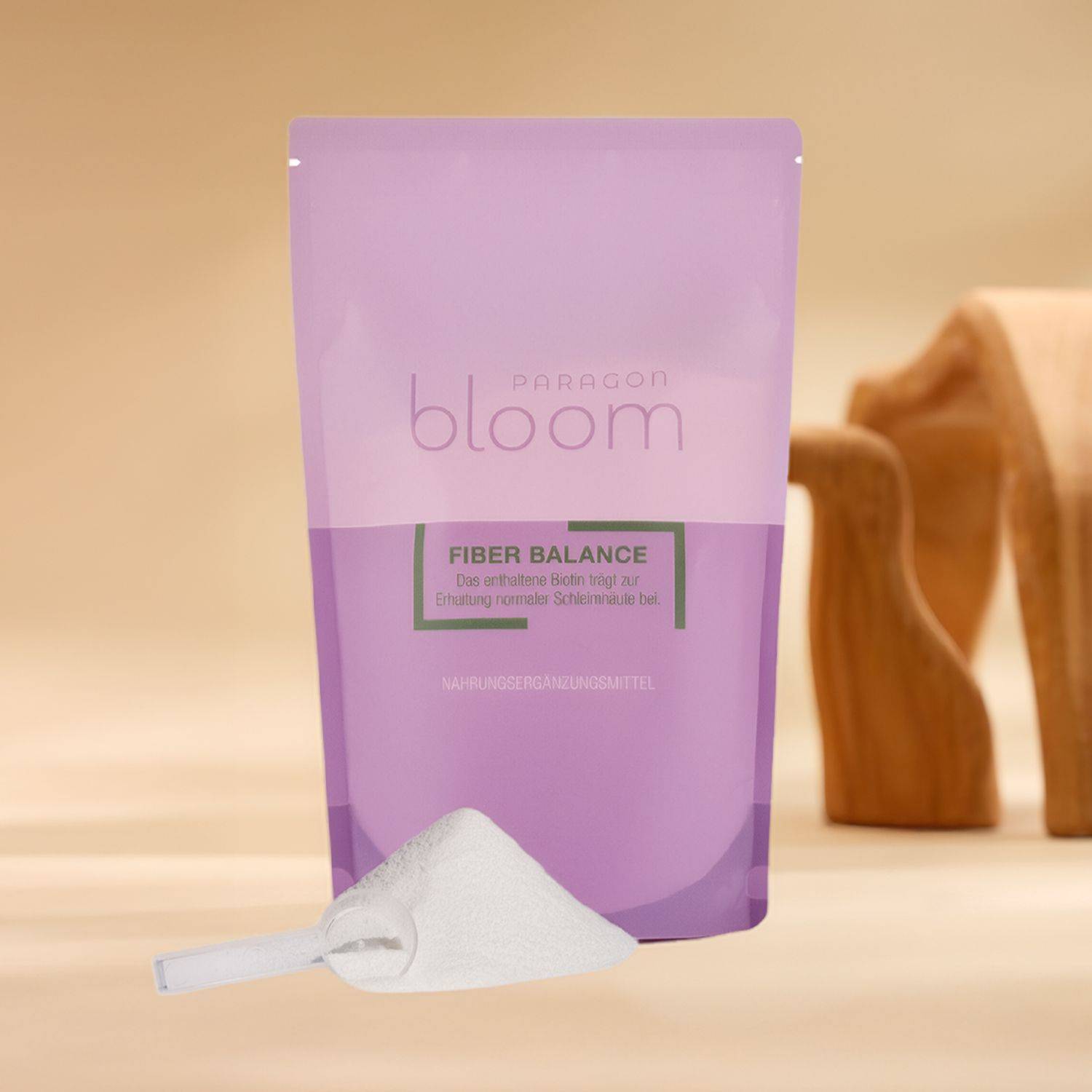 Fiber Balance von Paragon Bloom Violette Verpackung mit der Aufschrift 'paragon bloom FIBER BALANCE' neben einem weißen Messlöffel und einem hölzernen Dekoobjekt auf hellem Untergrund