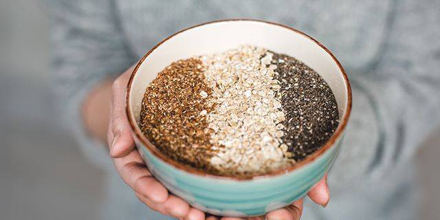 Schale mit gesunden Samen Hand hält Schale mit drei Sorten Samen oder Körnern in drei vertikalen Abschnitten