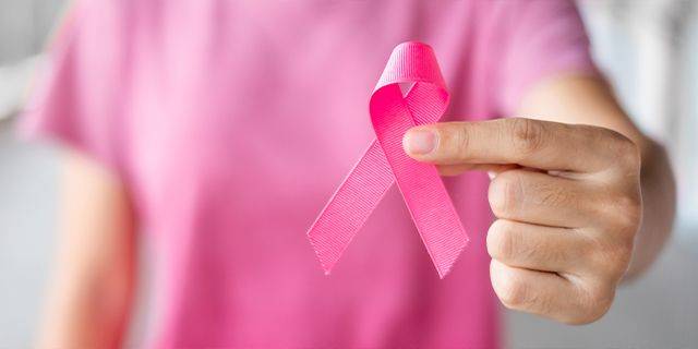 Krebserkrankungen in Deutschland Hand einer Person in rosa Oberteil hält eine pinke Schleife als Symbol für Brustkrebsbewusstsein