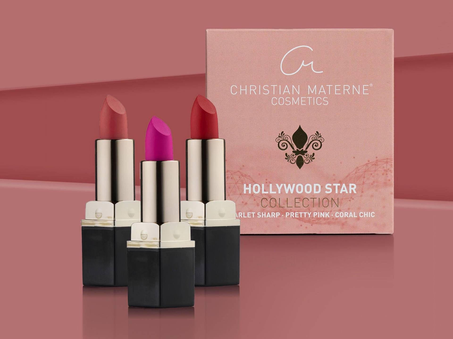 Pflegende Lippenstifte von Christian Materne Cosmetics Drei Lippenstifte in verschiedenen Rottönen vor einer rosa Verpackung mit der Aufschrift 'Christian Materne Cosmetics Hollywood Star Collection'